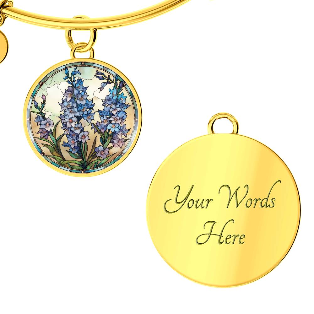 An elegant Gold pendant Larkspur Flower Bracelet. The colors are blue, purple, green and tan. This jewelry offers personalization with an engraving option for a name.