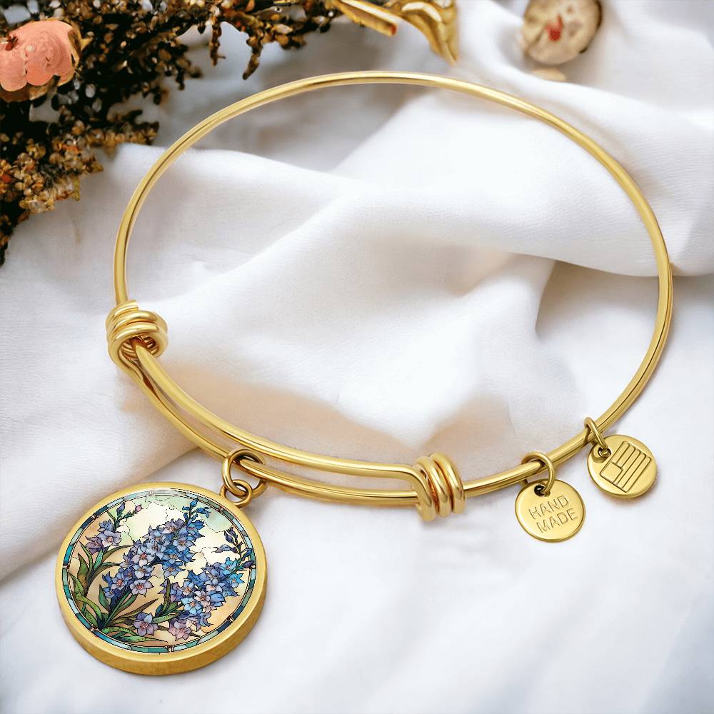 An elegant Gold pendant Larkspur Flower Bracelet. The colors are blue, purple, green and tan. This jewelry offers personalization with an engraving option for a name.