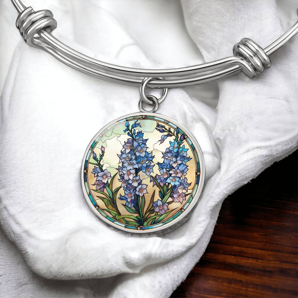 An elegant silver pendant Larkspur Flower Bracelet. The colors are blue, purple, green and tan. This jewelry offers personalization with an engraving option for a name.