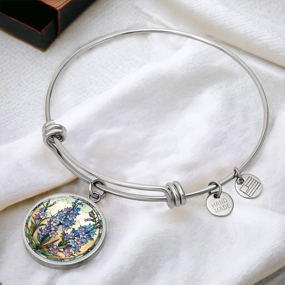 An elegant silver pendant Larkspur Flower Bracelet. The colors are blue, purple, green and tan. This jewelry offers personalization with an engraving option for a name.