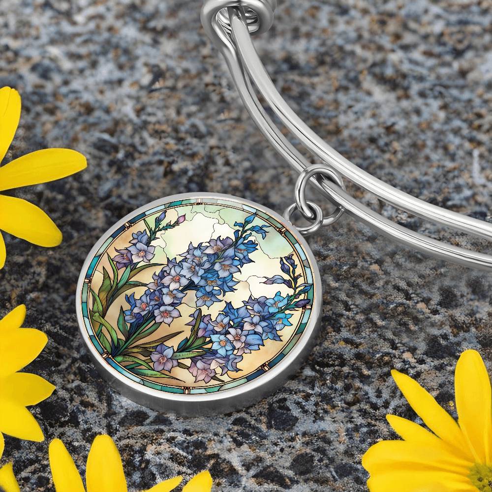 An elegant silver pendant Larkspur Flower Bracelet. The colors are blue, purple, green and tan. This jewelry offers personalization with an engraving option for a name.