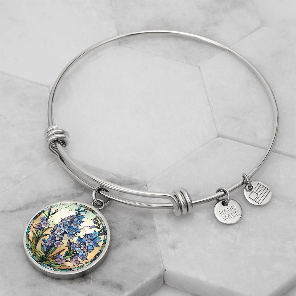 An elegant silver pendant Larkspur Flower Bracelet. The colors are blue, purple, green and tan. This jewelry offers personalization with an engraving option for a name.