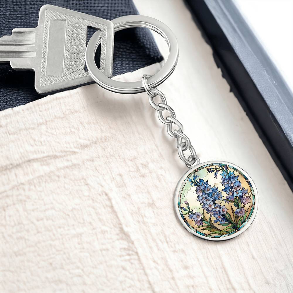 An elegant silver pendant Larkspur Flower Keychain. The colors are blue, purple, green and tan. This jewelry offers personalization with an engraving option for a name.