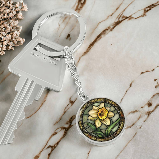 An Elegant Silver pendant Daffodil Necklace, March&#39;s birth month flower. Colors, Yellow flower, Green Grass, Brown Border, Dark Green background. This jewelry offers personalization with an engraving option for a name.