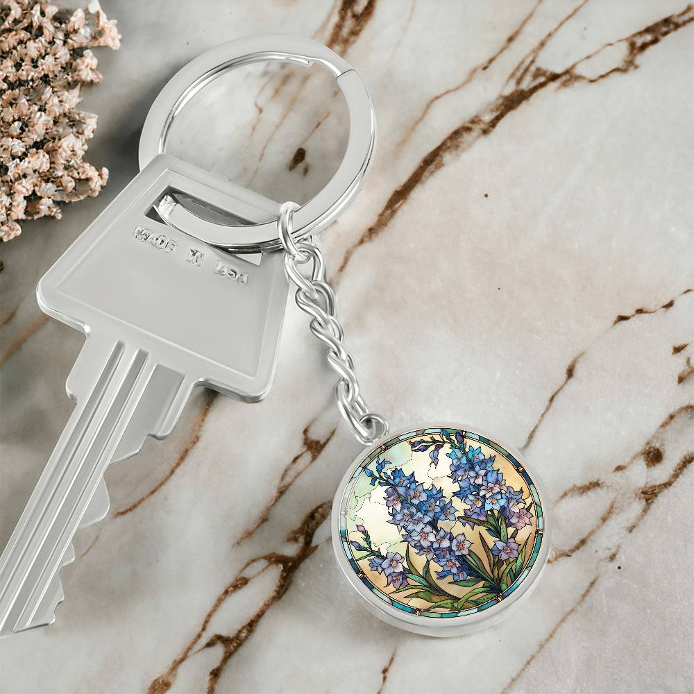 An elegant silver pendant Larkspur Flower Keychain. The colors are blue, purple, green and tan. This jewelry offers personalization with an engraving option for a name.