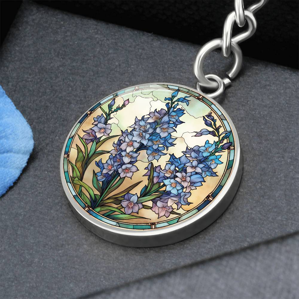 An elegant silver pendant Larkspur Flower Keychain. The colors are blue, purple, green and tan. This jewelry offers personalization with an engraving option for a name.