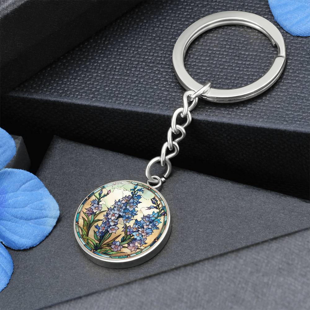 An elegant silver pendant Larkspur Flower Keychain. The colors are blue, purple, green and tan. This jewelry offers personalization with an engraving option for a name.