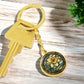 An Elegant Gold pendant Daffodil Necklace, March&#39;s birth month flower. Colors, Yellow flower, Green Grass, Brown Border, Dark Green background. This jewelry offers personalization with an engraving option for a name.