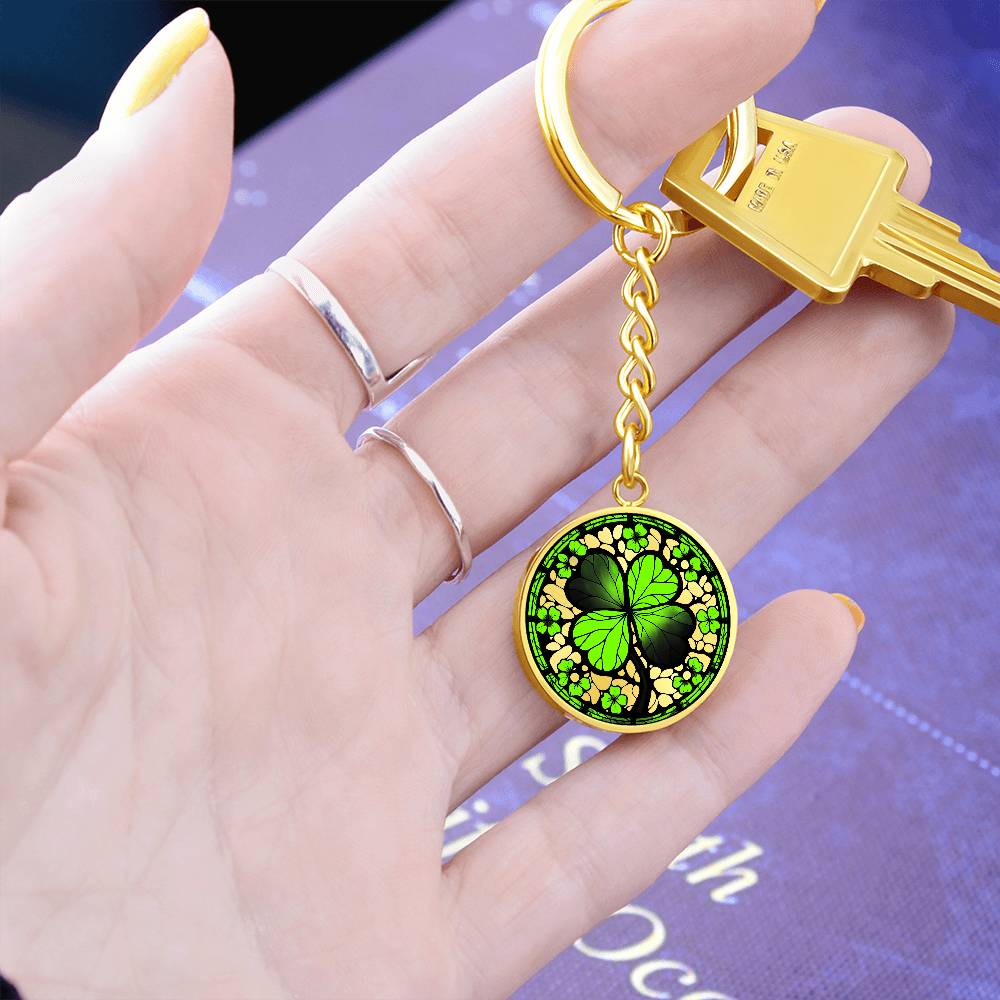 Woman holding an Elegant Gold pendant featuring a vivid Four Leaf Clover Keychain, set against a gold backdrop. This jewelry offers personalization with an engraving option for a name