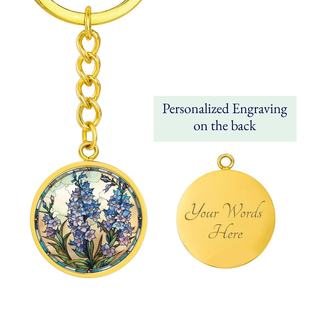 An elegant gold pendant Larkspur Flower Keychain. The colors are blue, purple, green and tan. This jewelry offers personalization with an engraving option for a name.